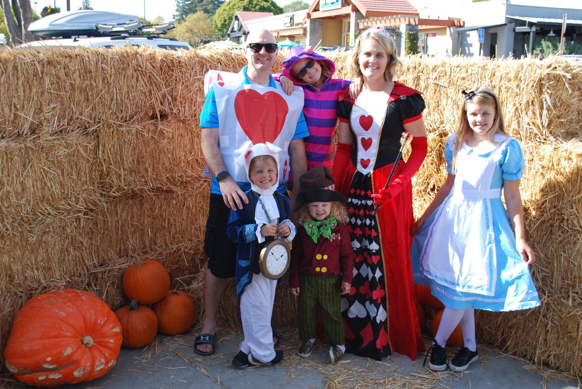 A family posing for a picture in front of hay bales and pumpkins