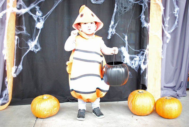 A child in a clown costume is holding a trick or treat bucket.