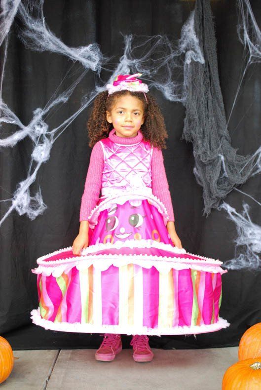 A little girl in a pink dress is holding a cake