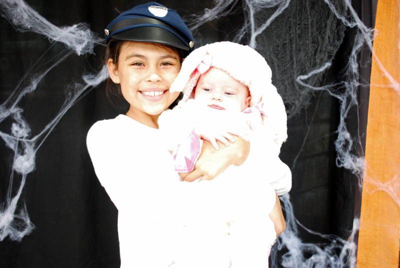 A little girl in a police hat is holding a baby