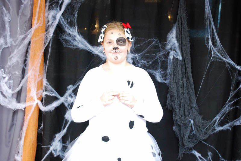 A girl in a dalmatian costume is standing in front of a spider web.