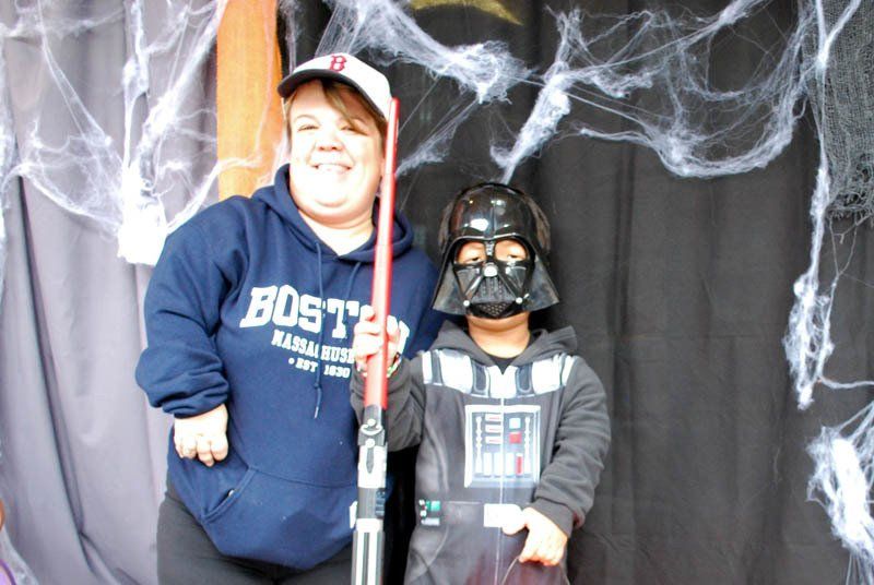 A boy wearing a darth vader mask stands next to a woman wearing a boston hoodie