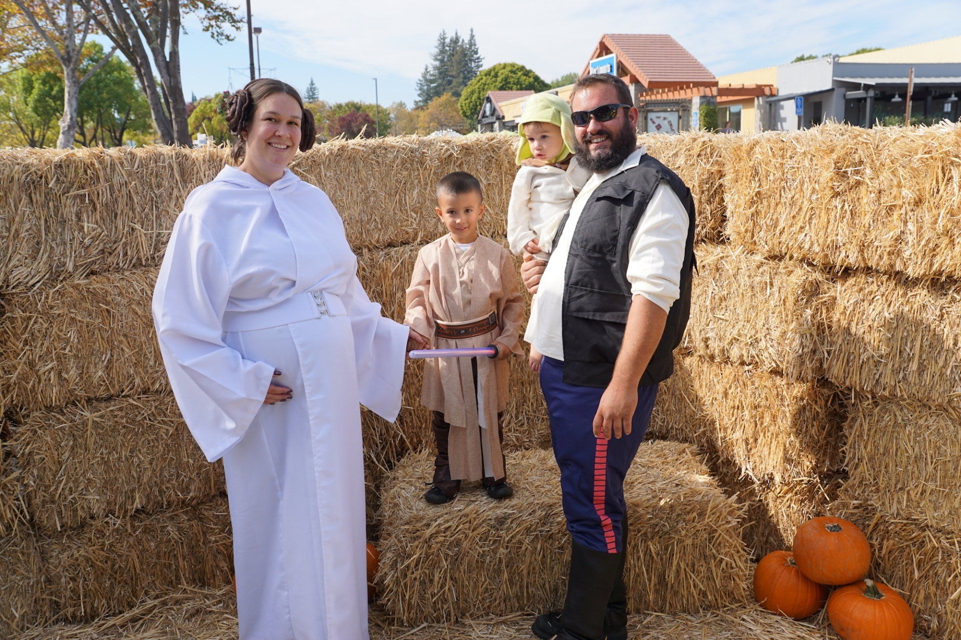 A family dressed in star wars costumes standing next to hay bales.