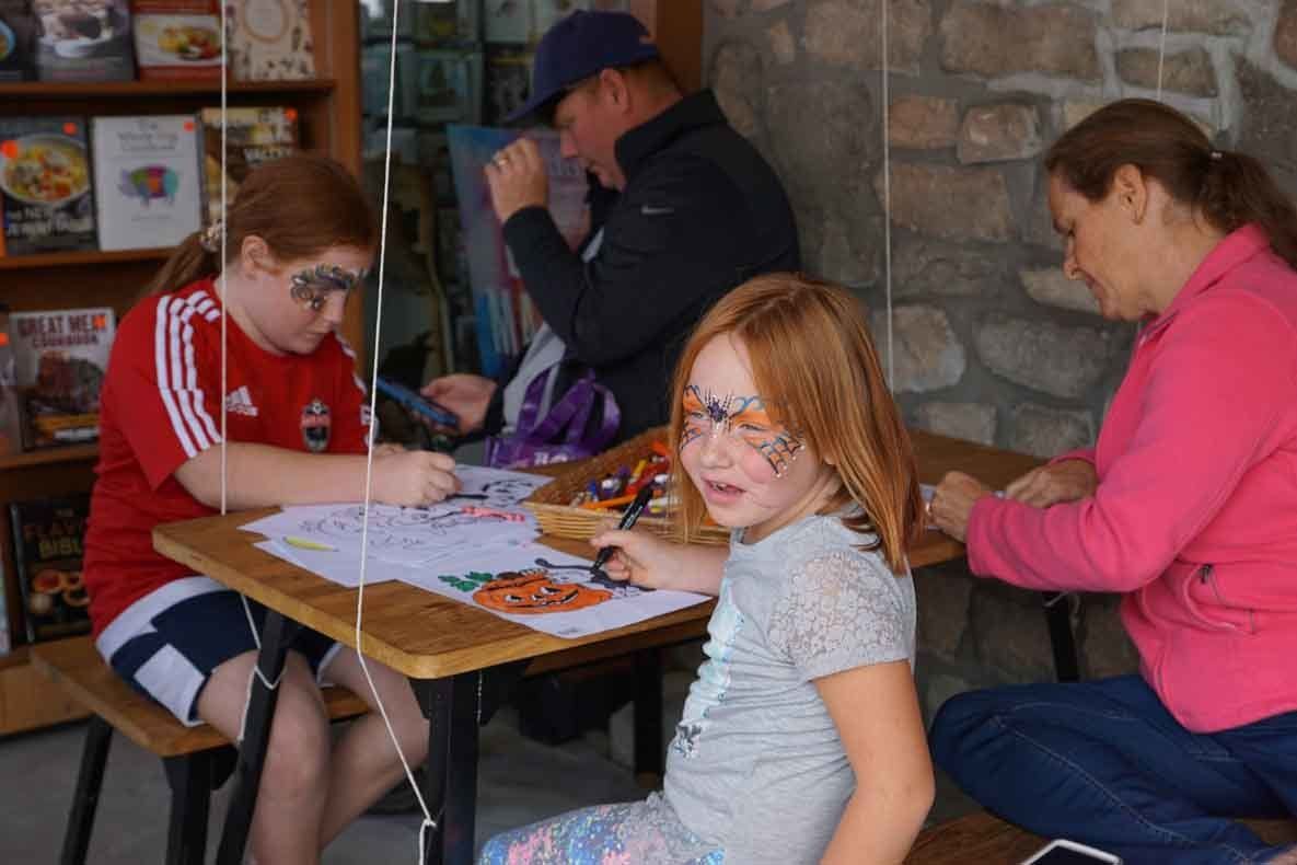 A group of children are sitting at a table with their faces painted.