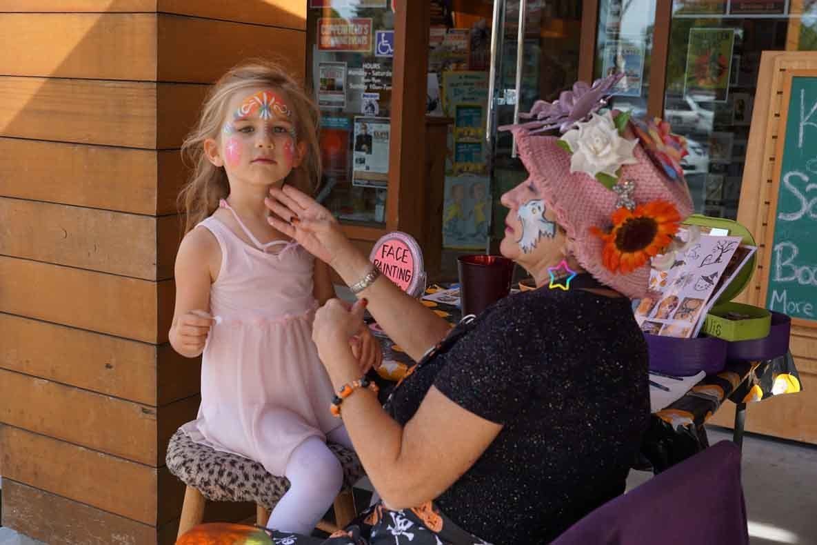 A woman is painting a little girl 's face.