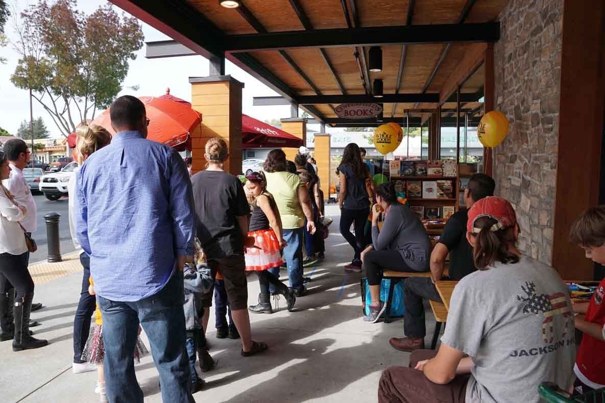 A group of people are standing outside of a restaurant.