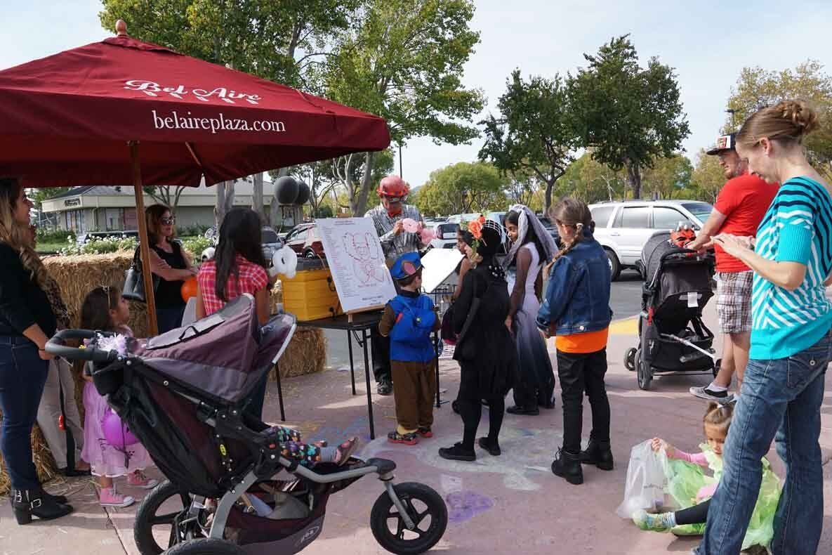 A group of people are standing around a stroller under an umbrella.