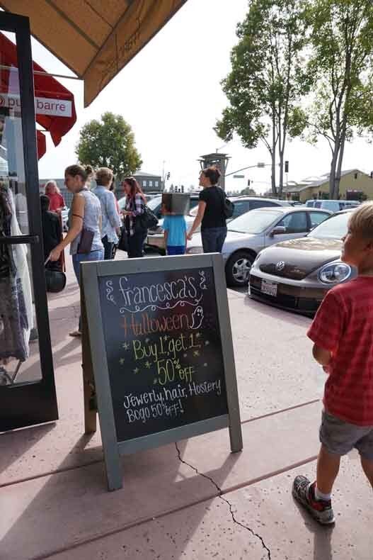 A boy standing in front of a sign that says ' jacob 's ' on it