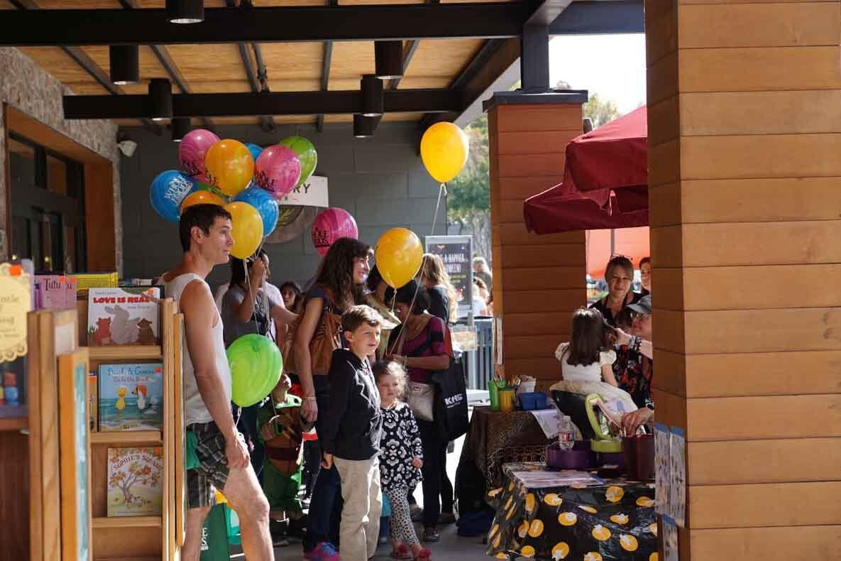 A group of people are standing around a table with balloons on it