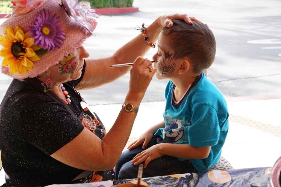 A woman is painting a child 's face with a spoon.