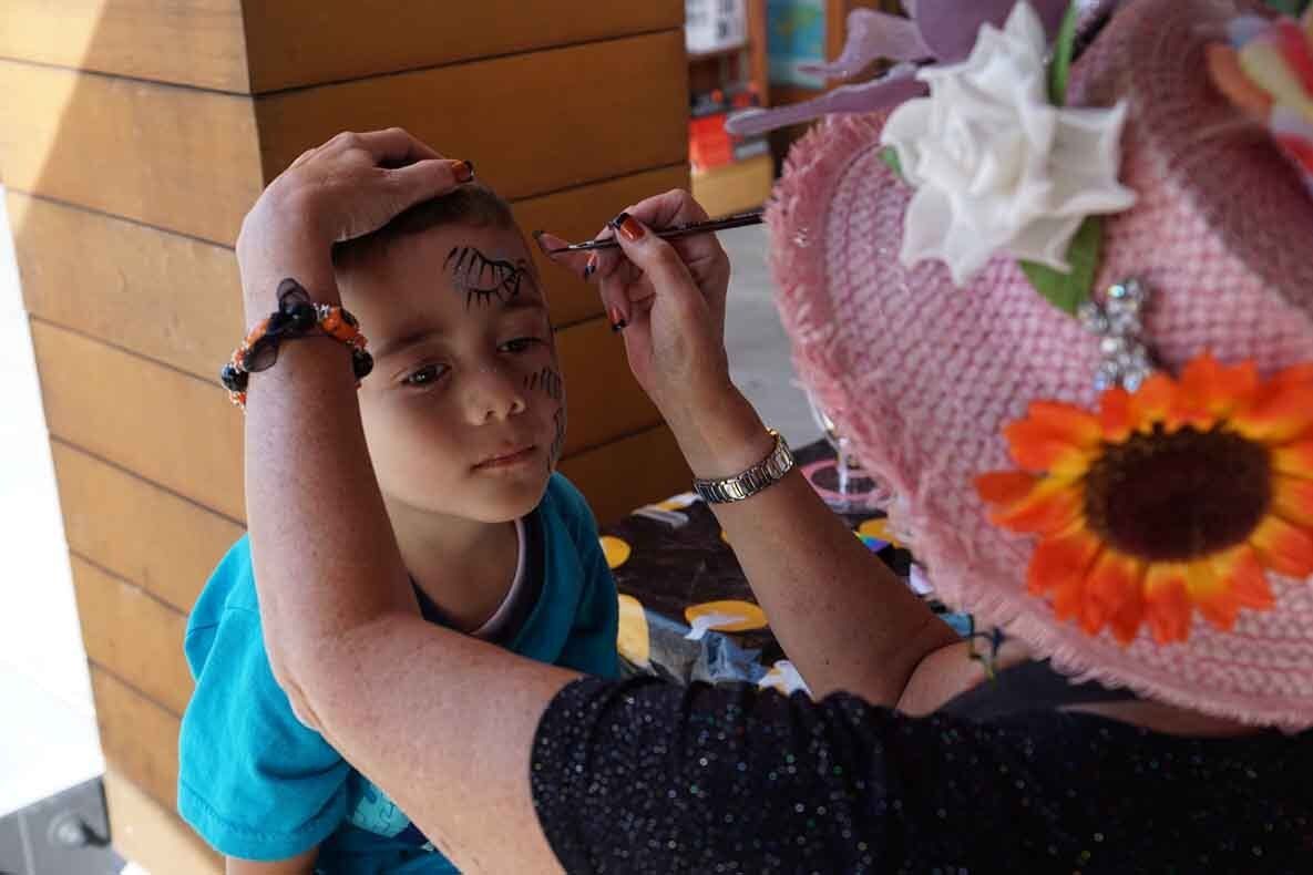 A woman in a pink hat is painting a child 's face.