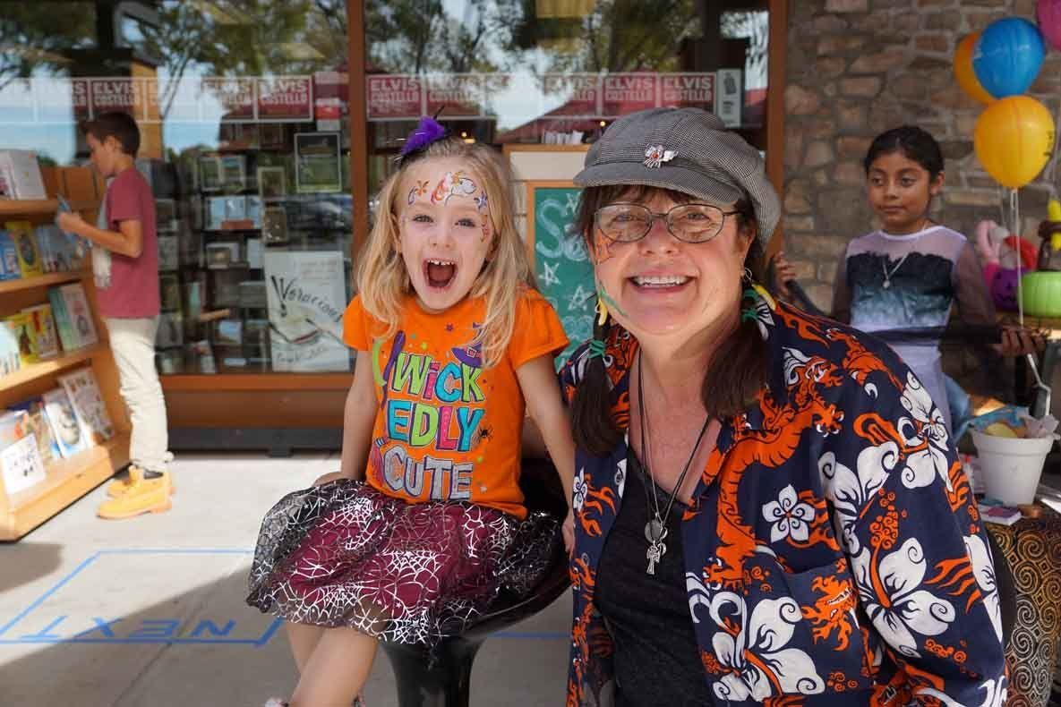 A woman and a little girl are posing for a picture in front of a book store.