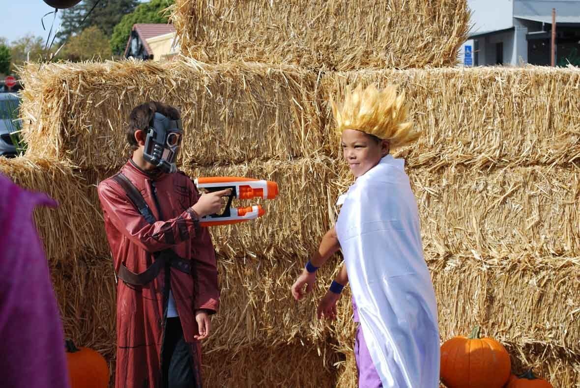 A man in a gas mask is standing next to a girl in a white cape.
