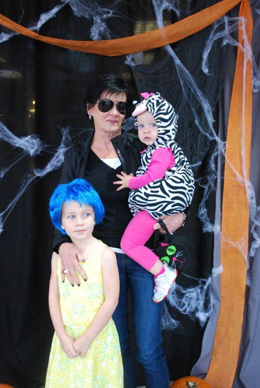 A woman is holding a little girl in a zebra costume.