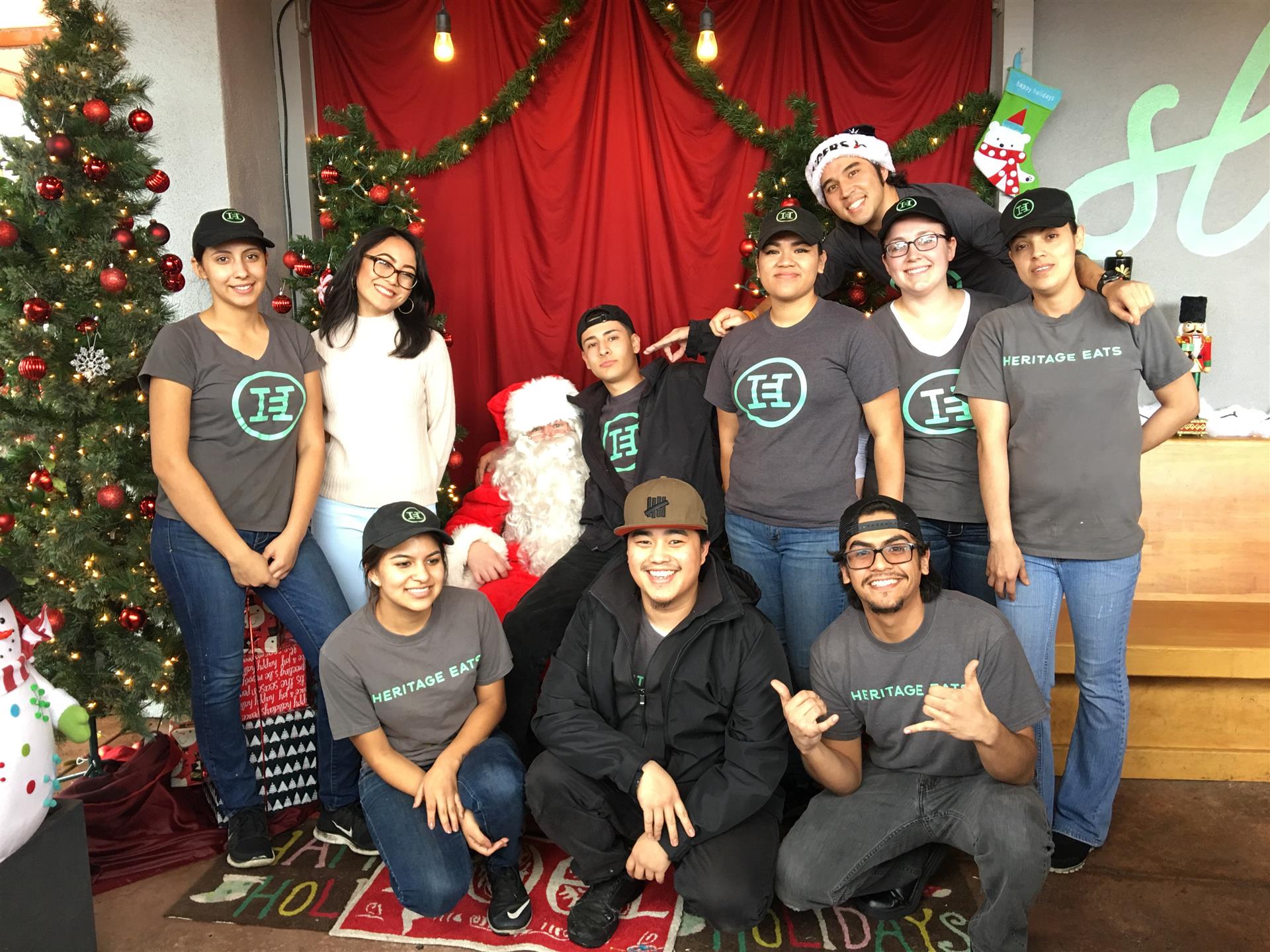 A group of people are posing for a picture with santa claus in front of a christmas tree.