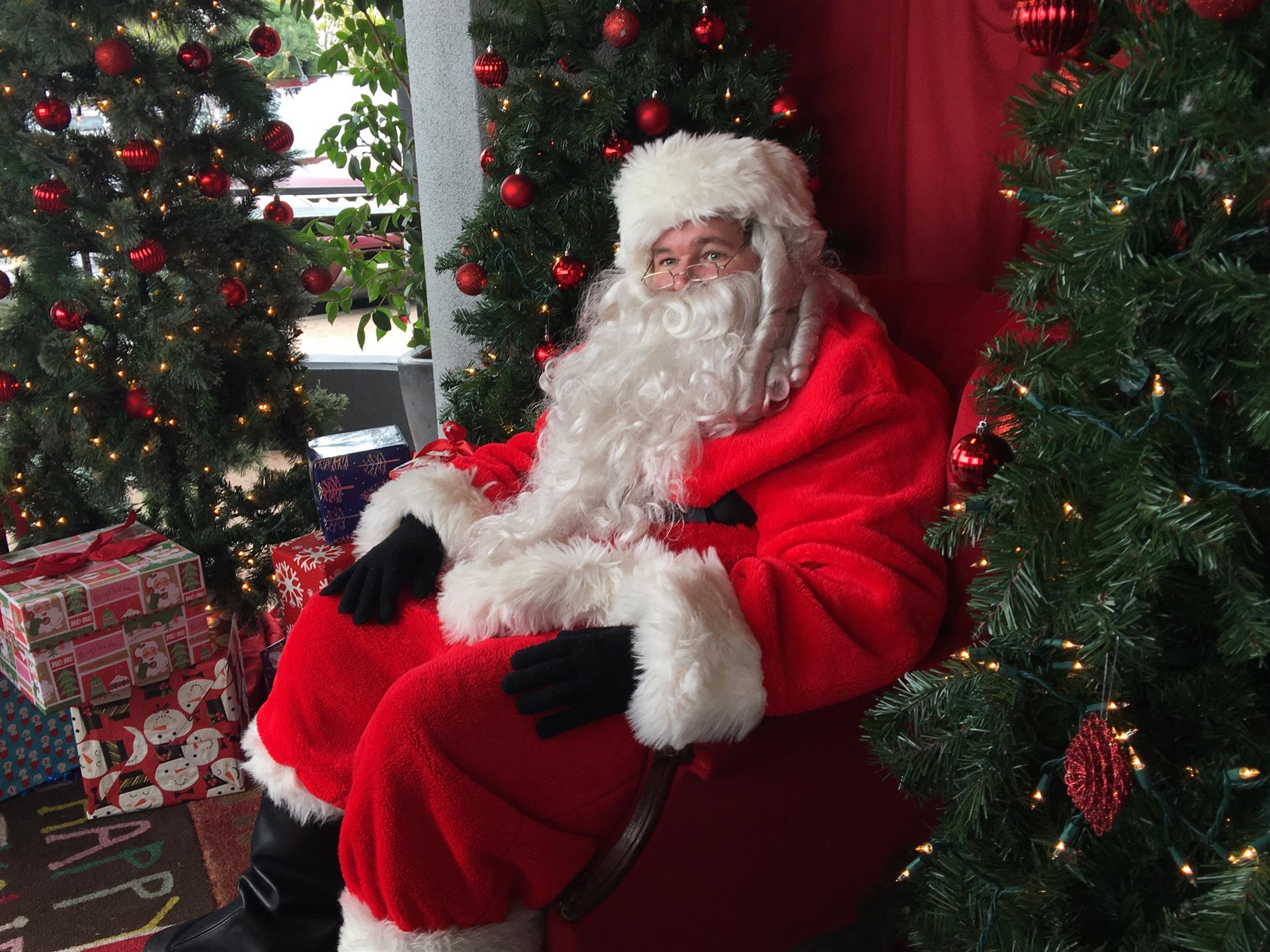 Santa claus is sitting in front of a christmas tree