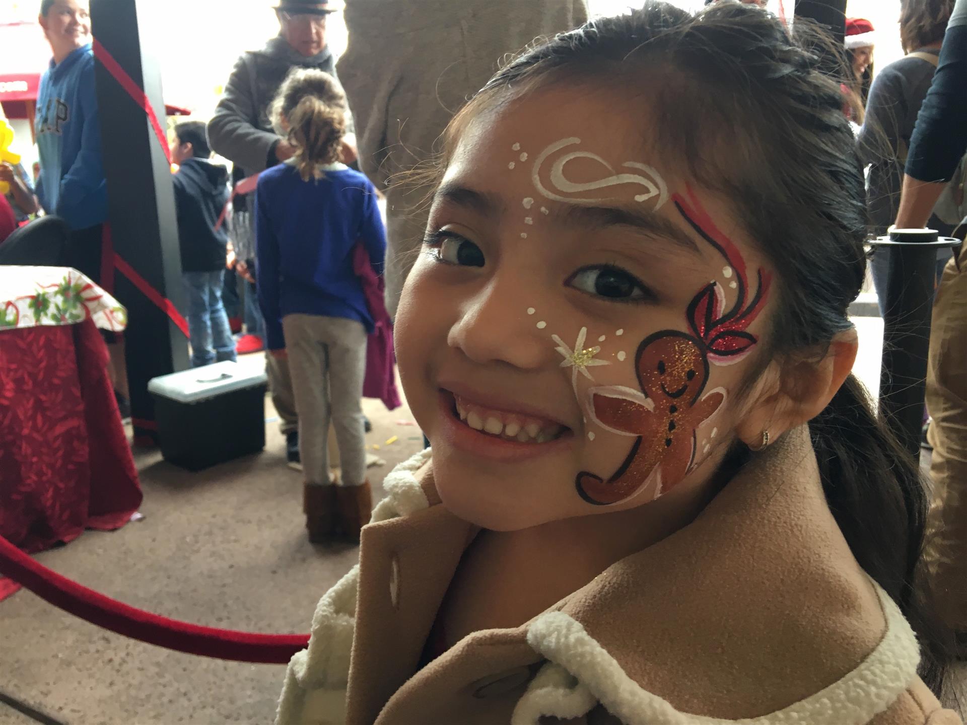 A little girl with a gingerbread man painted on her face