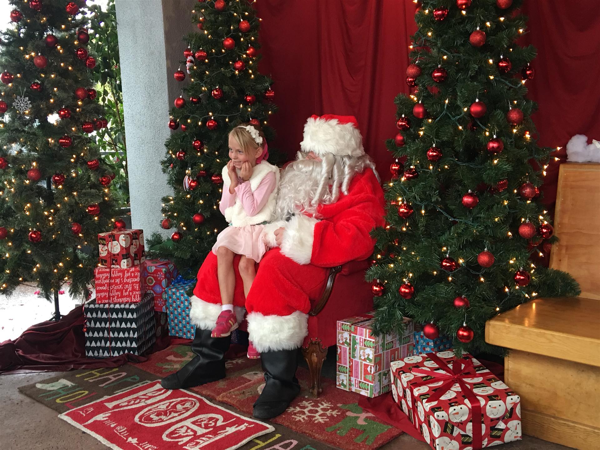 A little girl is sitting on the lap of santa claus.