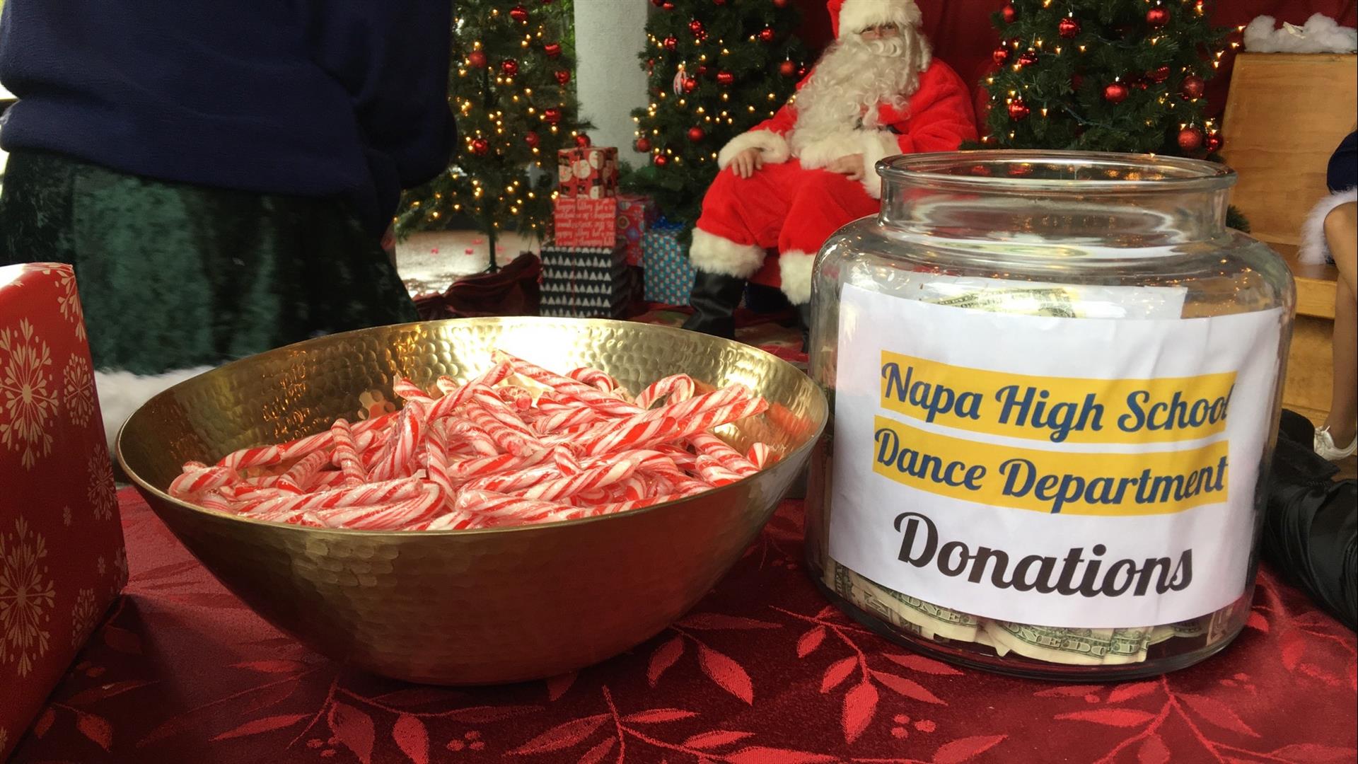 A jar of donations next to a bowl of candy canes.