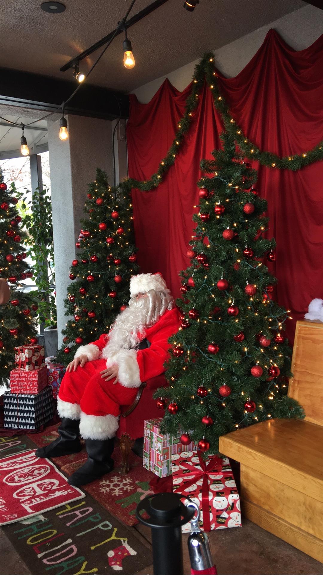 Santa claus is sitting in a chair in front of a christmas tree.