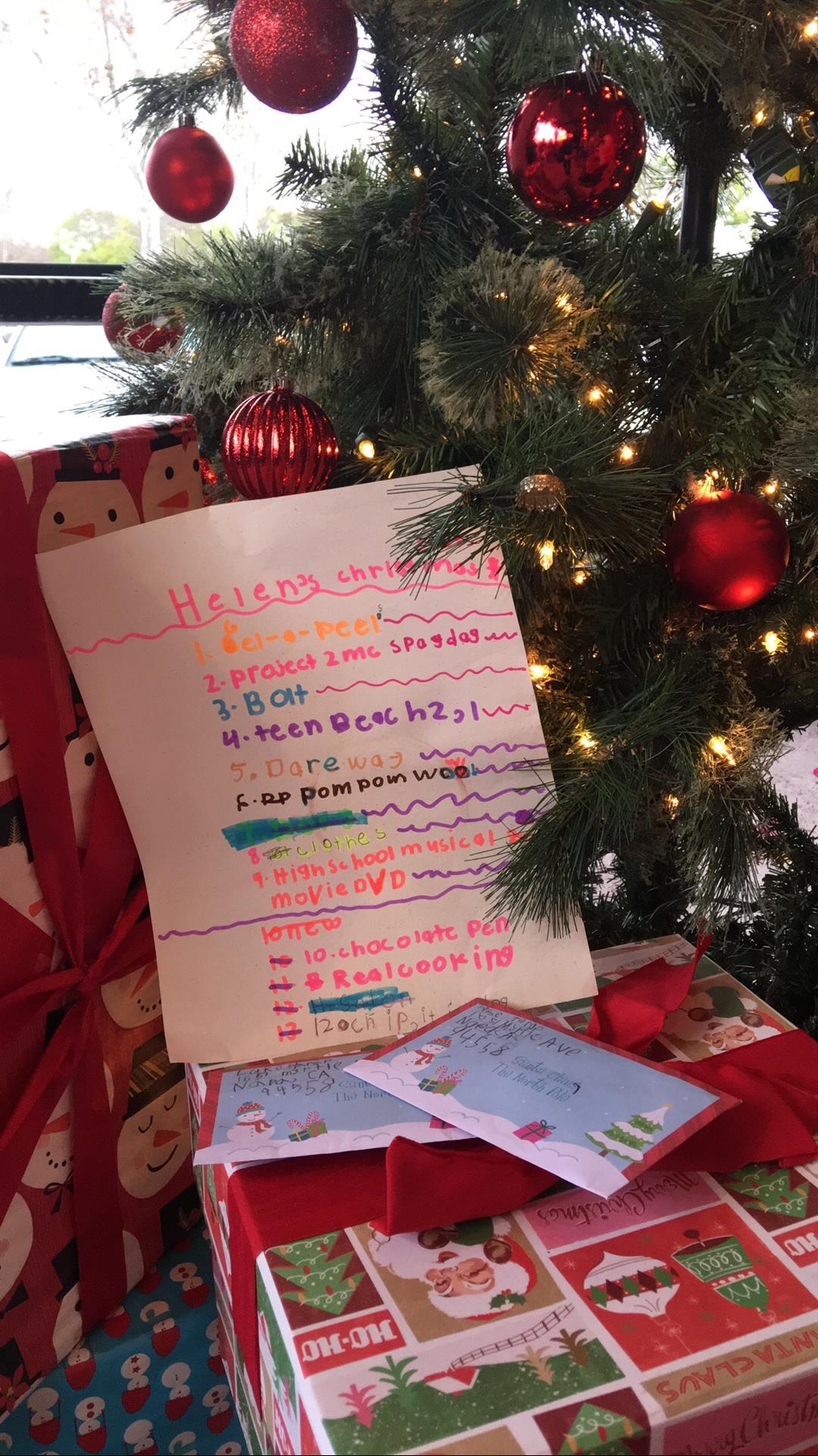 A letter from santa claus is sitting under a christmas tree.