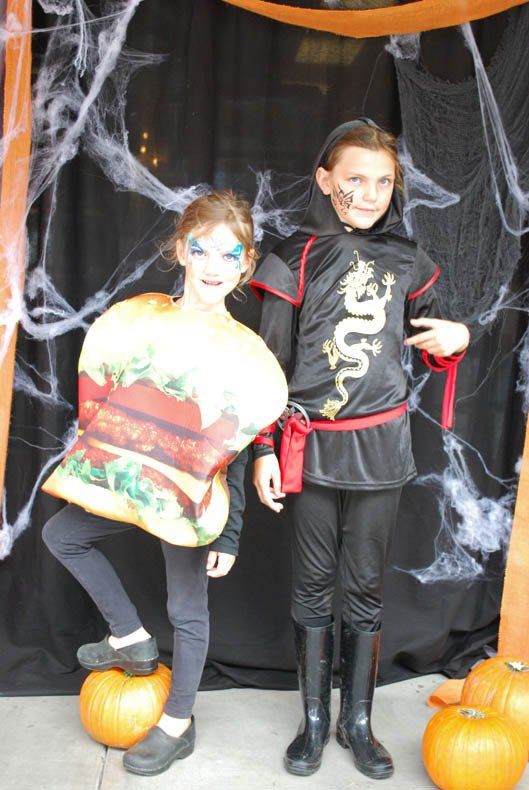 Two children in halloween costumes are posing for a picture