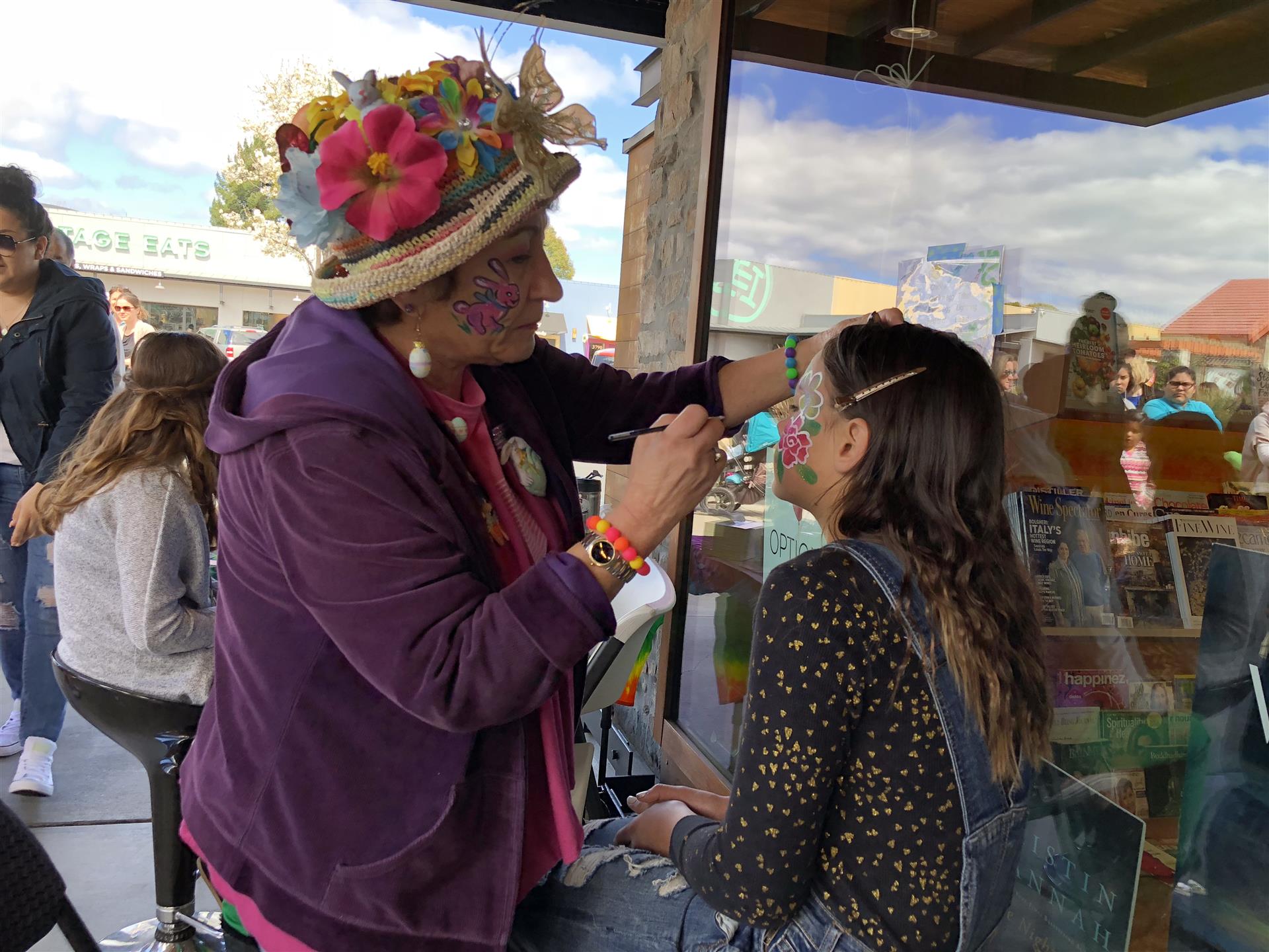 A woman is painting a girl 's face at a festival.