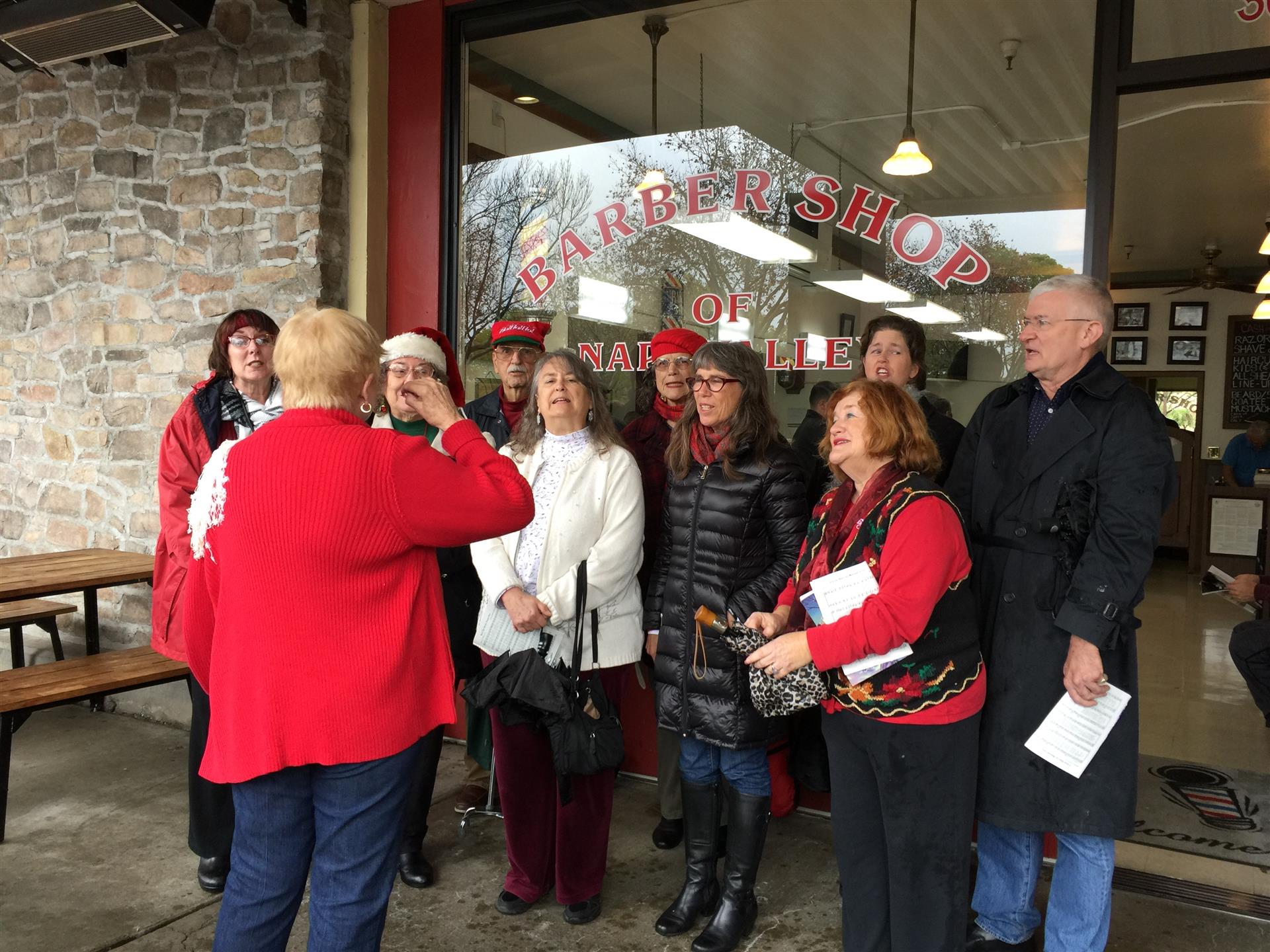 A group of people are standing outside of a barber shop.