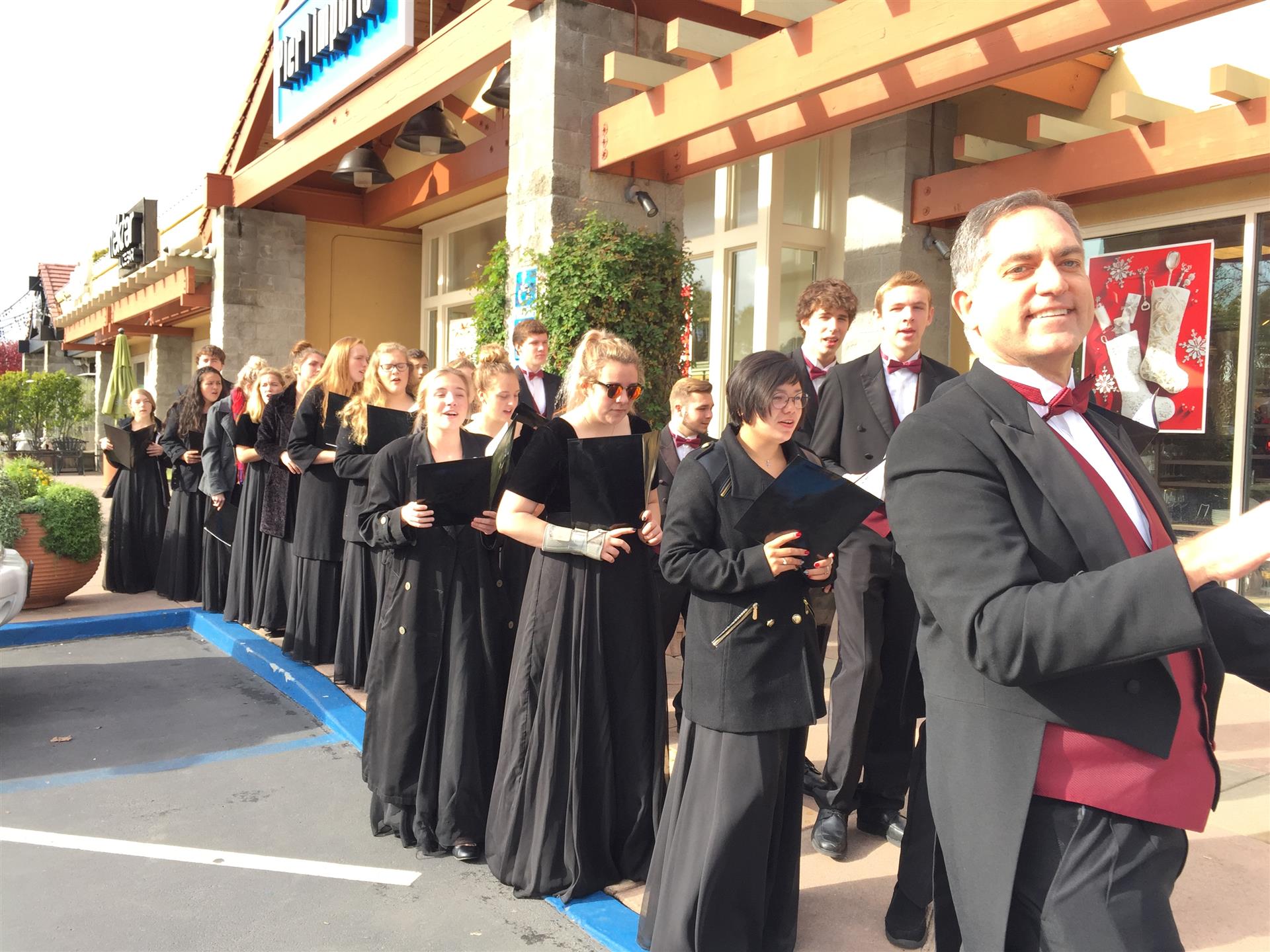 A man in a tuxedo stands in front of a choir