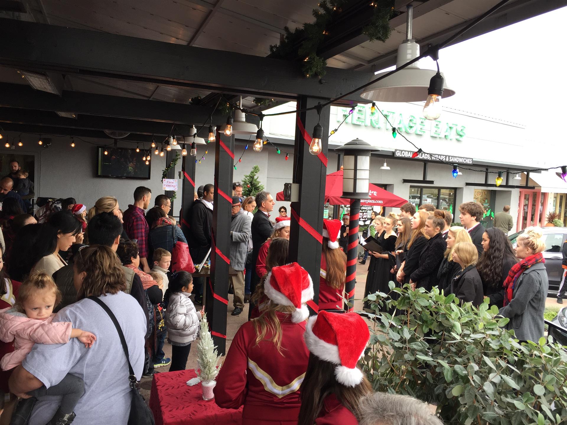 A group of people wearing santa hats are standing outside of a building.