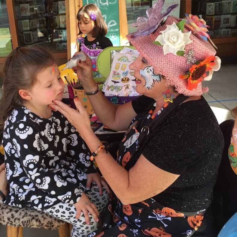A woman is painting a little girl 's face