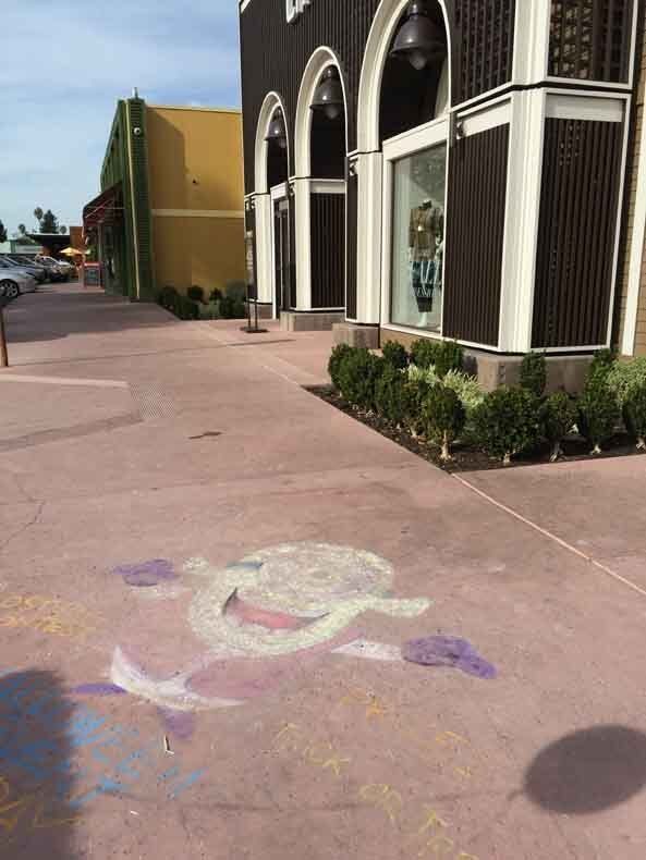 A chalk drawing of a turtle on the sidewalk in front of a building.