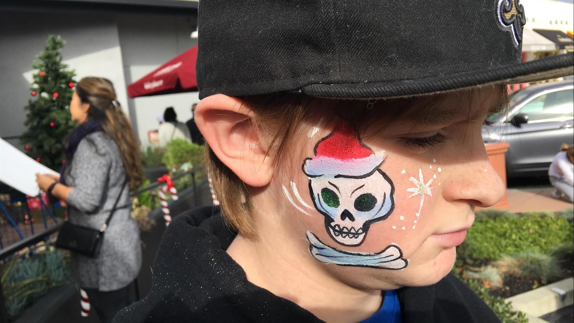 A young boy with a skull painted on his face.