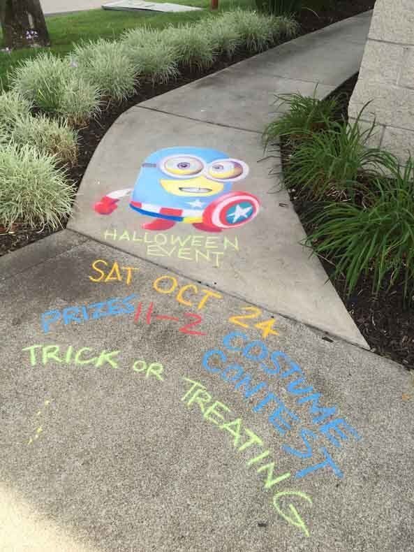 A chalk drawing of a minion dressed as captain america on a sidewalk.