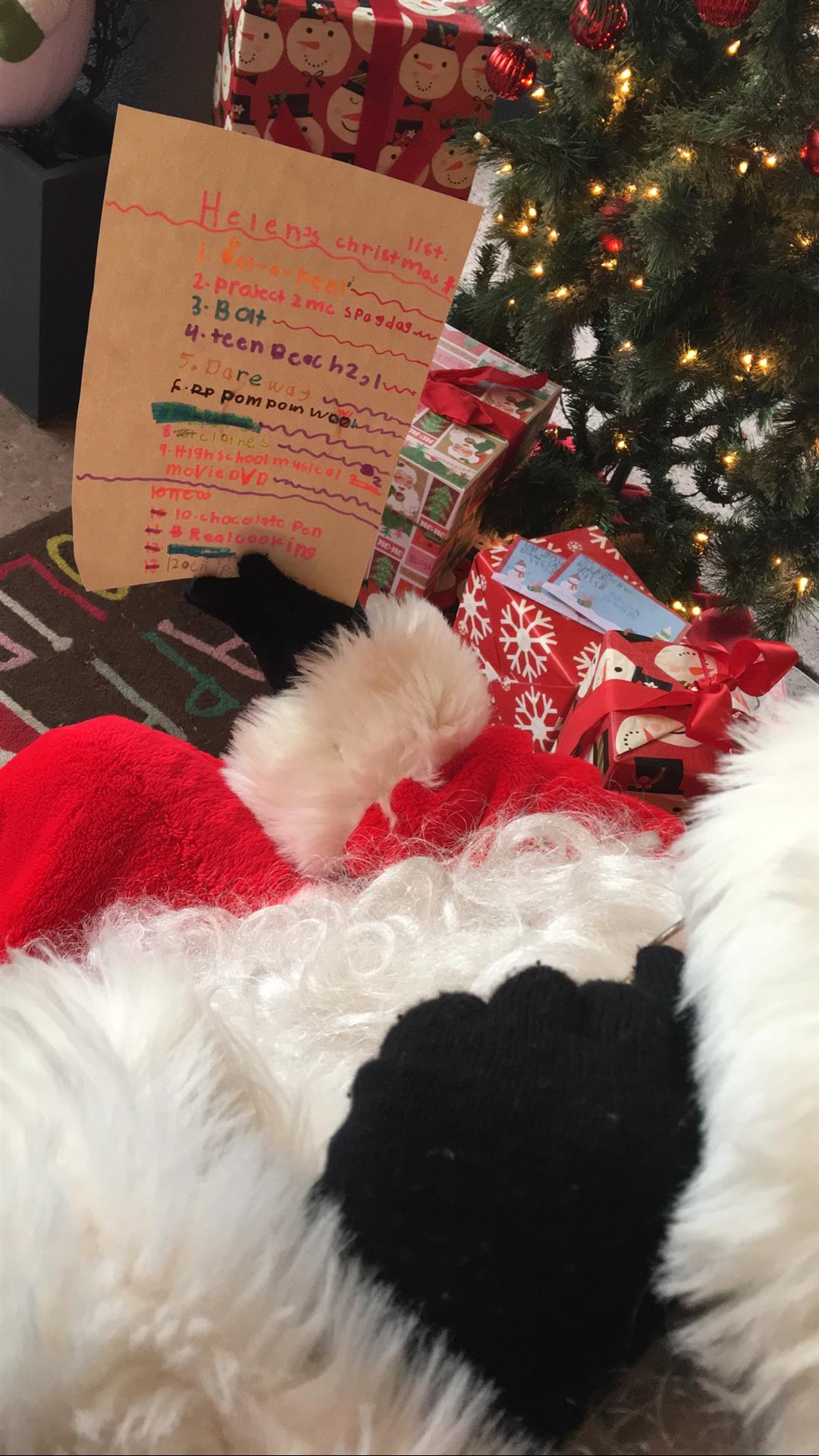 A stuffed animal is laying in front of a christmas tree.