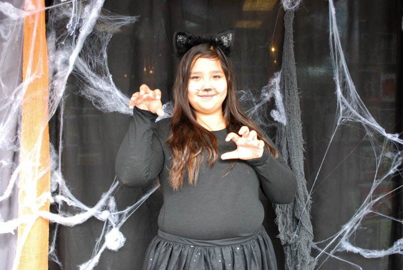 A girl in a cat costume is standing in front of a spider web.