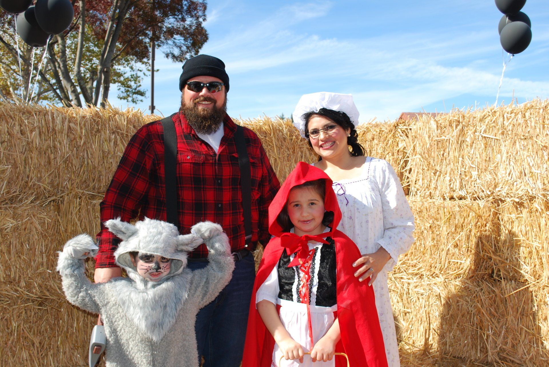 A family is posing for a picture in front of hay bales.