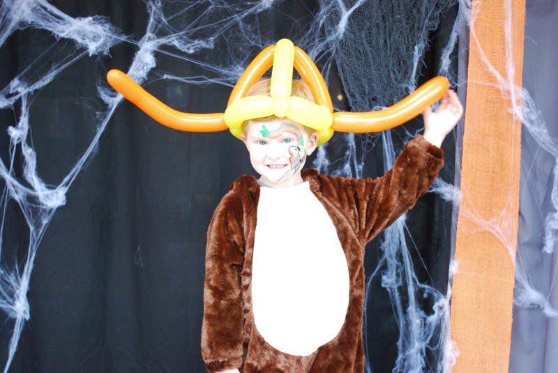 A little boy in a monkey costume with balloons on his head