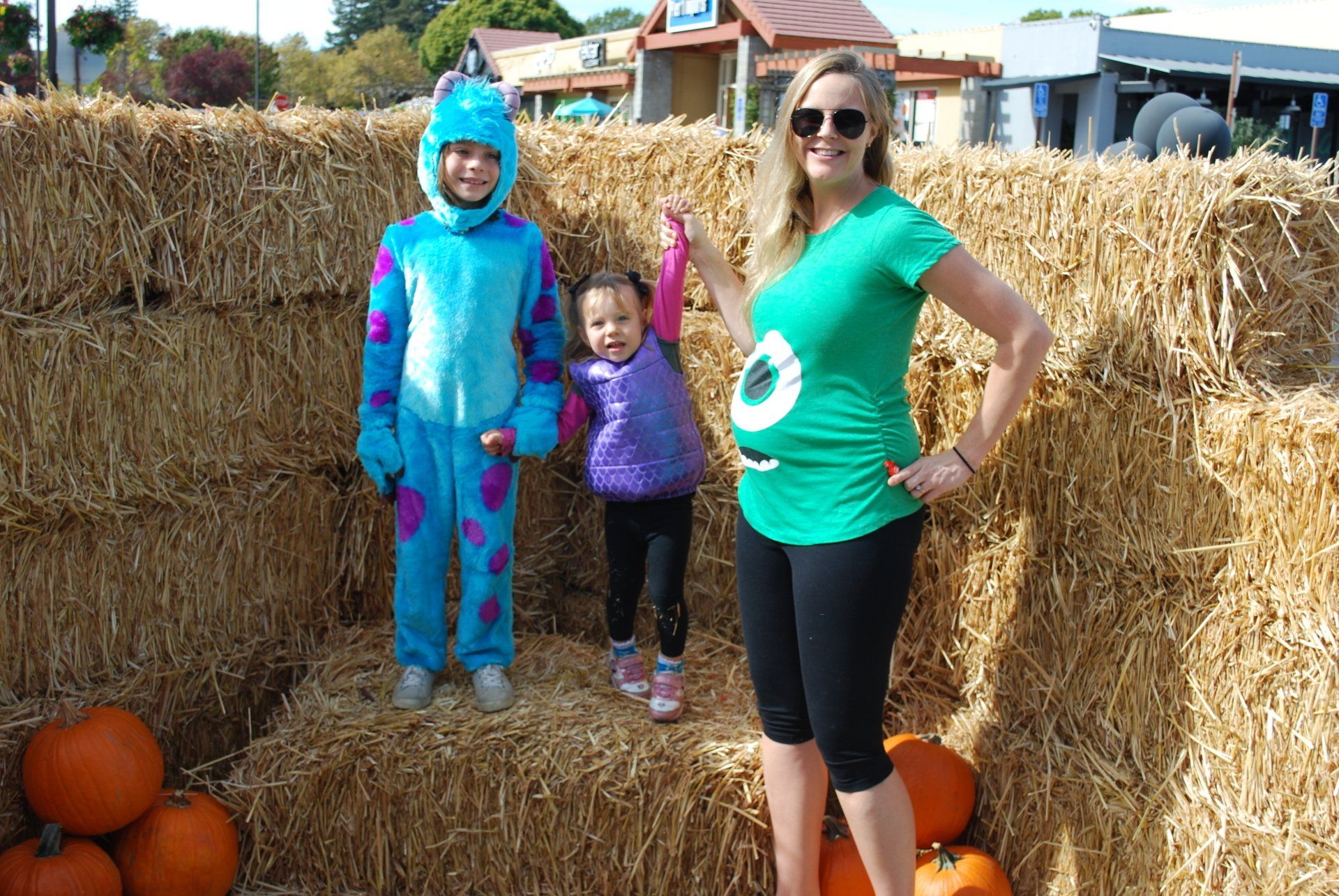 A woman and two children are posing for a picture in a pumpkin patch.