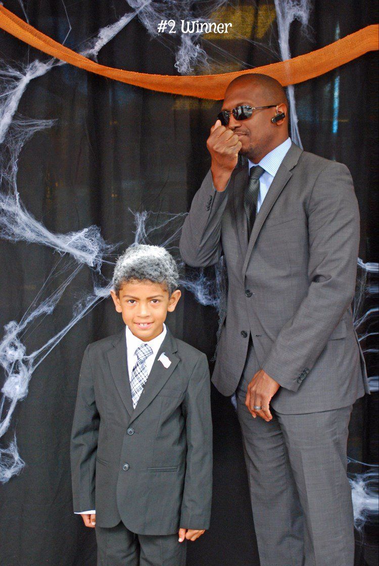 A man in a suit is talking on a walkie talkie next to a boy in a suit