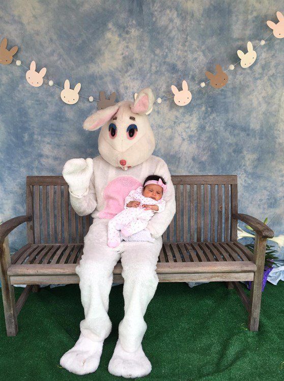 An easter bunny is sitting on a bench holding a baby