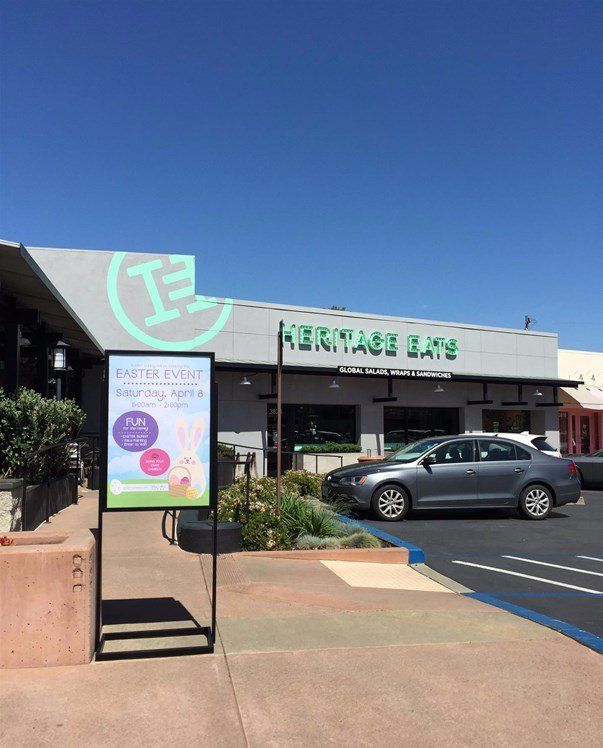 A car is parked in front of a restaurant called heritage eats