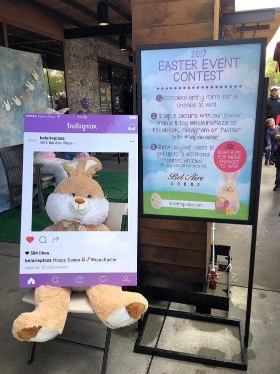 A stuffed bunny is sitting next to a sign that says easter event contest