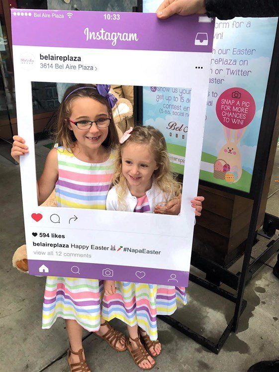 Two little girls are posing for a picture with an instagram frame.