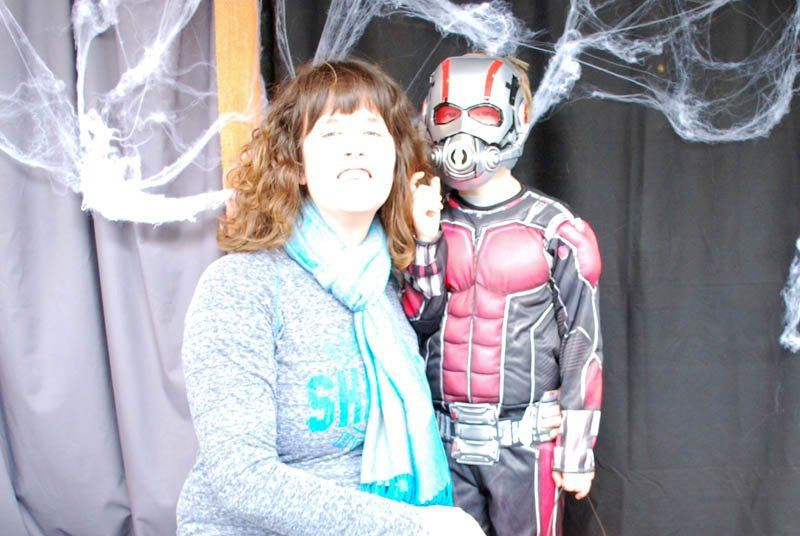 A woman is standing next to a boy in an ant man costume