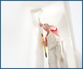 A professional painter and decorator painting a wall with a roller