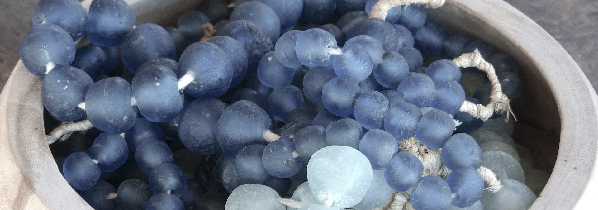 Blue grapes piled in a metal bowl, with a few lighter grapes mixed in