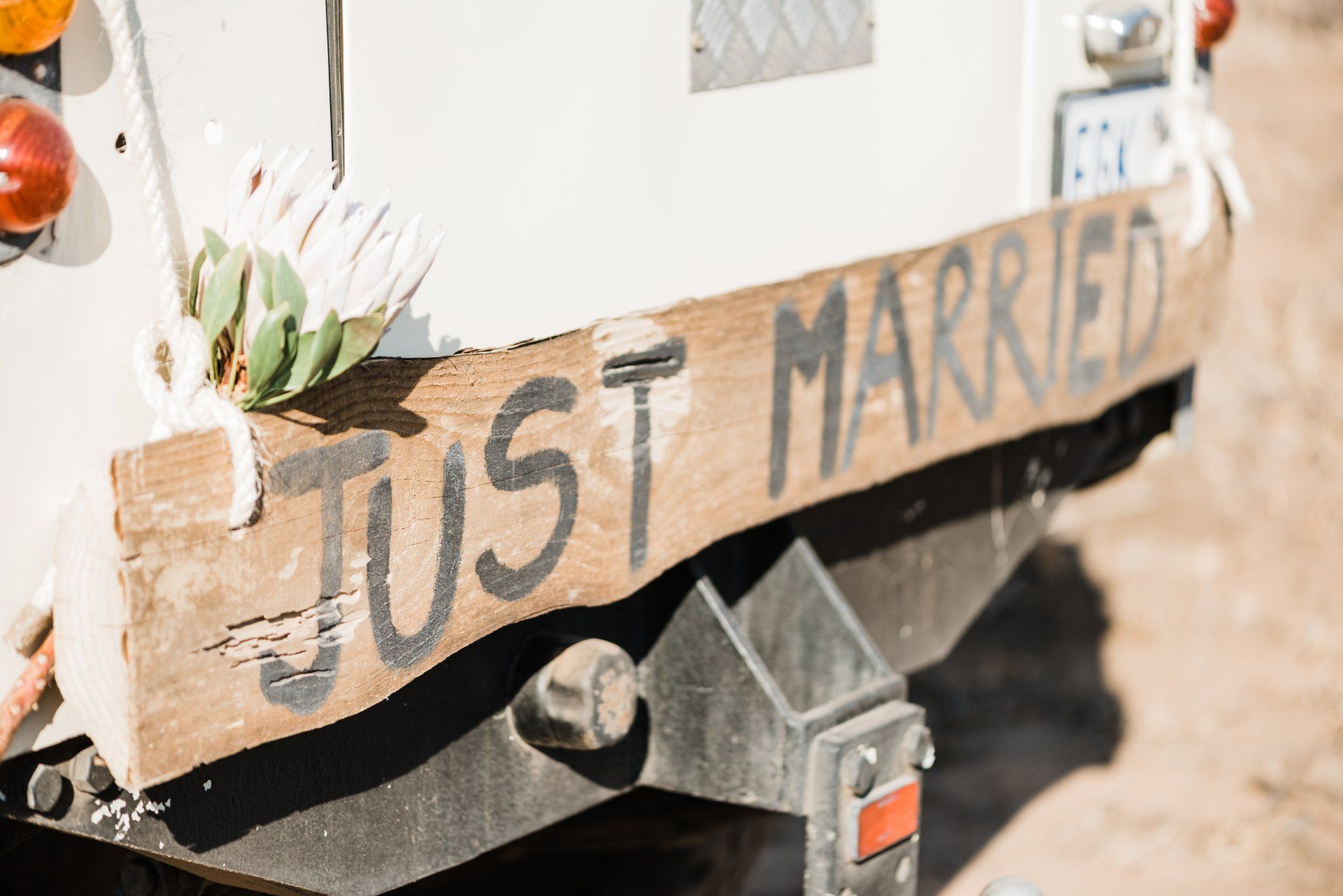 Wooden “Just Married” sign on a decorated vehicle at a wedding