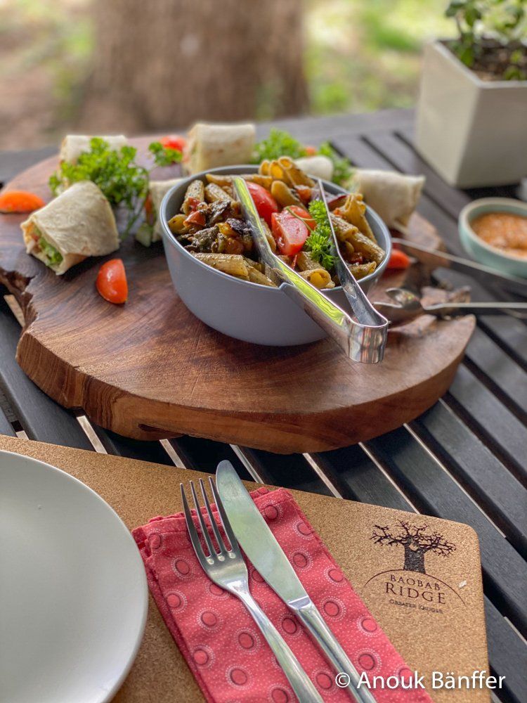 Tacos in a gray bowl on a wooden tray with a fork and knife on an outdoor table.