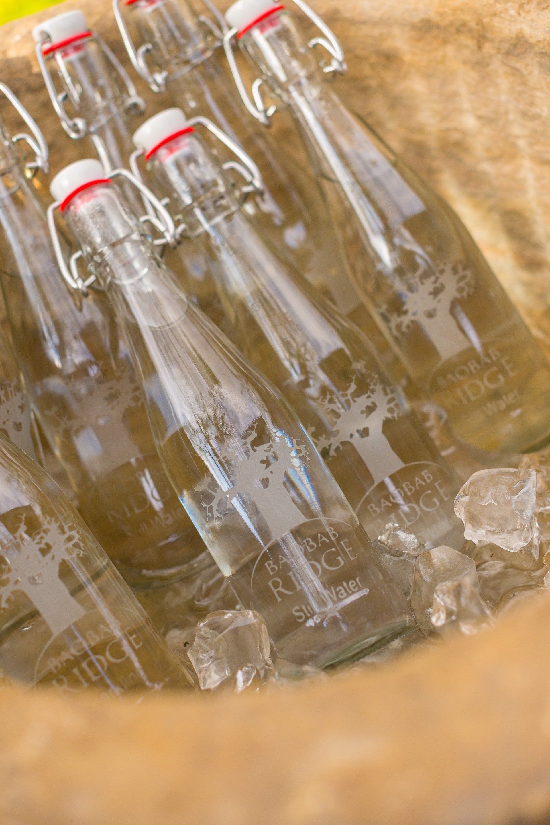 Glass bottles with red caps resting in a wooden crate, viewed from above.